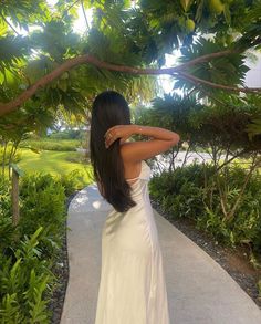 a woman in a white dress standing on a path with her back to the camera