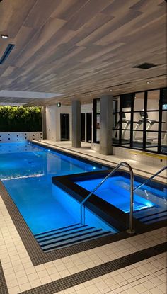 an indoor swimming pool with steps leading up to it and blue lights on the ceiling