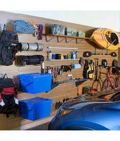 a blue car parked in front of a wooden wall filled with sports gear and equipment