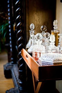 an assortment of glass bottles and vases sitting on a table in front of a mirror