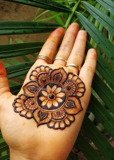 a woman's hand with henna tattoos on it and palm leaves in the background