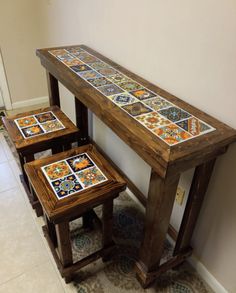 three wooden tables sitting next to each other on top of a tile covered floor in front of a white wall