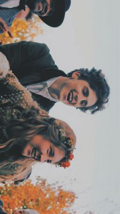 three young people standing next to each other in front of trees with leaves on them