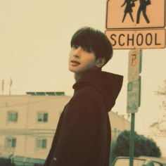 a boy standing in front of a school crossing sign with his hands on his hips