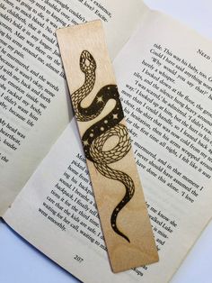 a bookmark with an image of a snake on it sitting next to an open book