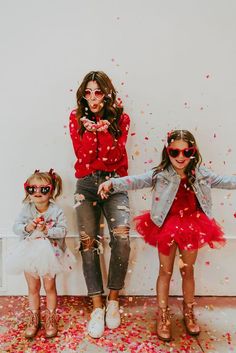 three girls in red and white outfits standing next to each other with confetti all over them