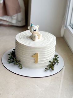 a white cake with a teddy bear on top