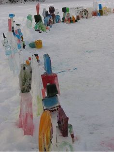 many colorful glass bottles are lined up in the snow, and there is no image here to provide a caption for