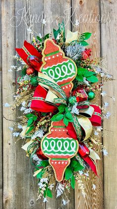 a christmas wreath hanging on the side of a wooden fence with red and green decorations