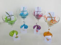 there are four wine glasses with cards in them