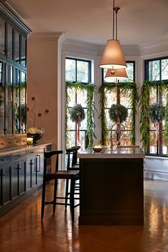 a kitchen with an island and lots of plants in the window sill, along with two chairs