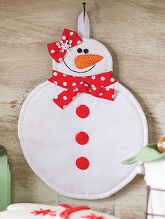 a snowman hanging from the side of a wall next to two cakes on a table