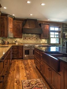 a large kitchen with wooden floors and granite counter tops, along with an area rug on the hardwood flooring