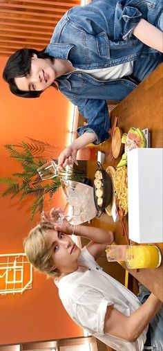 two people standing in front of a table with food and drinks