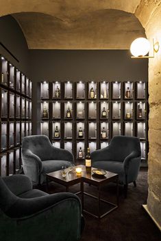 a dimly lit room with two chairs and a coffee table in front of the wall