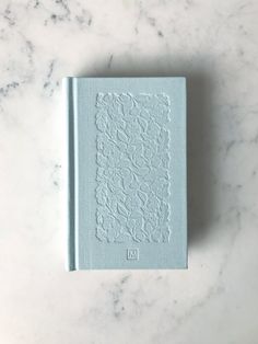 a blue book sitting on top of a marble countertop next to a white wall