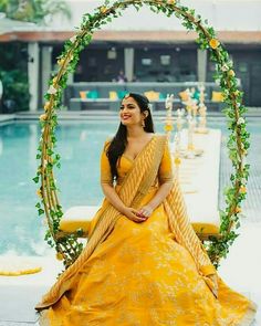 a woman in a yellow dress sitting on a chair with greenery around her neck