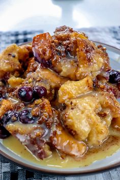 a white plate topped with bananas and blueberries next to a cup of coffee on a checkered table cloth