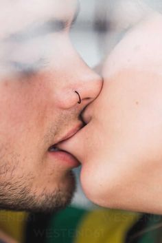 a man and woman kissing each other with their noses close to one another while looking into the distance