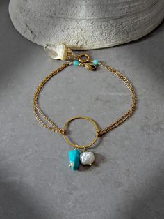 Capture the impactful symbology of natural gemstones with this dainty chain artisan circle bracelet. Adorned with a single natural freshwater keshi pearl, genuine Arizona Sleeping Beauty turquoise, micro faceted amazonite rounds & a gold accented natural shell pendant, this intentional bracelet reflects the symboli Gold Rondelle Bohemian Jewelry, Bohemian Gold Rondelle Jewelry, Gold Round Pearl Bracelet In Bohemian Style, Gold Round Bohemian Pearl Bracelet, Gold Bohemian Round Pearl Bracelet, Gold Amazonite Bracelet Jewelry, Gold Amazonite Bracelet, Rondelle Pearl Chain Jewelry As Gift, Gold Bohemian Jewelry With Pearl Charm