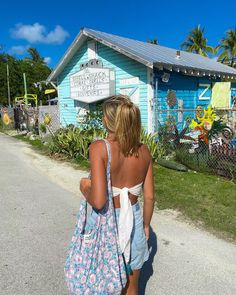 a woman is walking down the street carrying a blue and white bag in her hand