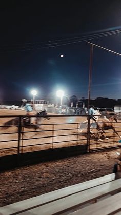 the horses are racing on the track at night