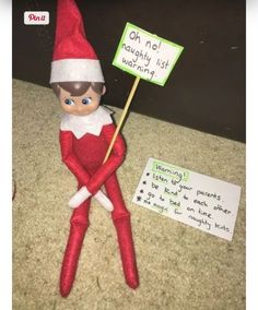 an elf holding a sign sitting on the ground