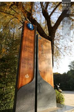 two metal and wood sculptures sitting in front of a tree