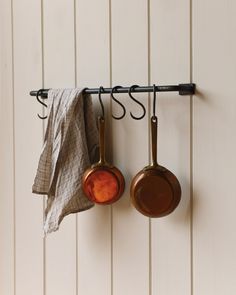 two pots and pans hanging on a wall