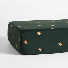 a green wrapping paper with gold and white flowers on it's edges, sitting on a white surface