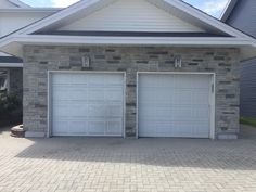 two white garage doors in front of a brick house