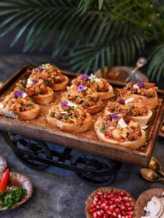 a wooden tray filled with lots of food on top of a table next to other foods