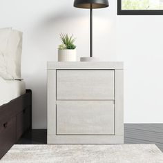 a white nightstand sitting next to a bed on top of a carpeted bedroom floor