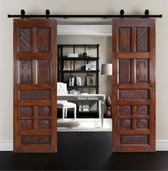 an open wooden door leading to a living room with a desk and bookshelf