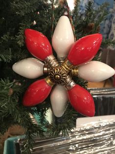 a red and white flower ornament hanging from a christmas tree