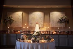 a table topped with a white cake covered in lots of candles next to tall vases filled with flowers