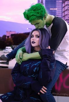 a man and woman dressed up as the joker and green haired girl in front of a cityscape