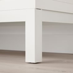 a close up of a white table on a wood floor with no one around it