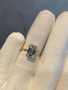 a woman's hand holding a ring with an emerald colored stone in the middle