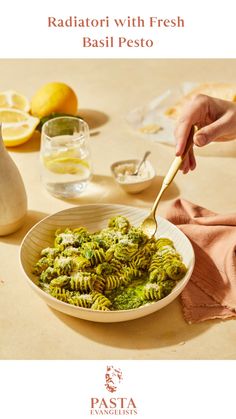 a person eating pasta with fresh basil pesto in a white bowl on a table