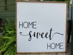 a sign that says home sweet home next to a potted plant on a porch