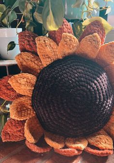 a sunflower made out of crochet sits on a table next to a potted plant