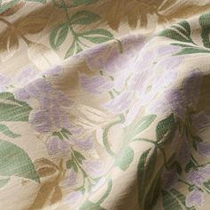 the fabric has flowers on it and is green, purple, and beige colors with leaves