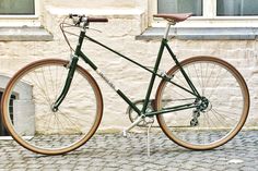 a green bike parked on the side of a street next to a building with windows