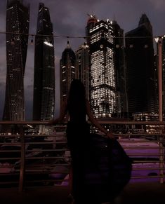 a woman standing in front of a city skyline at night