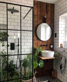 a bathroom with black and white tiles, a round mirror, potted plants and a sink