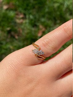 a woman's hand with a ring on it and grass in the back ground