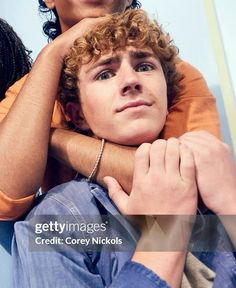 two young men sitting next to each other with their arms around one another's shoulders