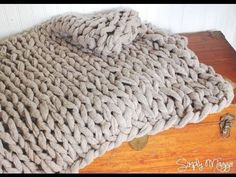 a large chunky blanket sitting on top of a wooden table next to a drawer