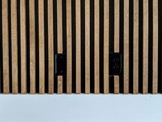 two black electrical outlets are mounted to the side of a wooden wall with vertical slats